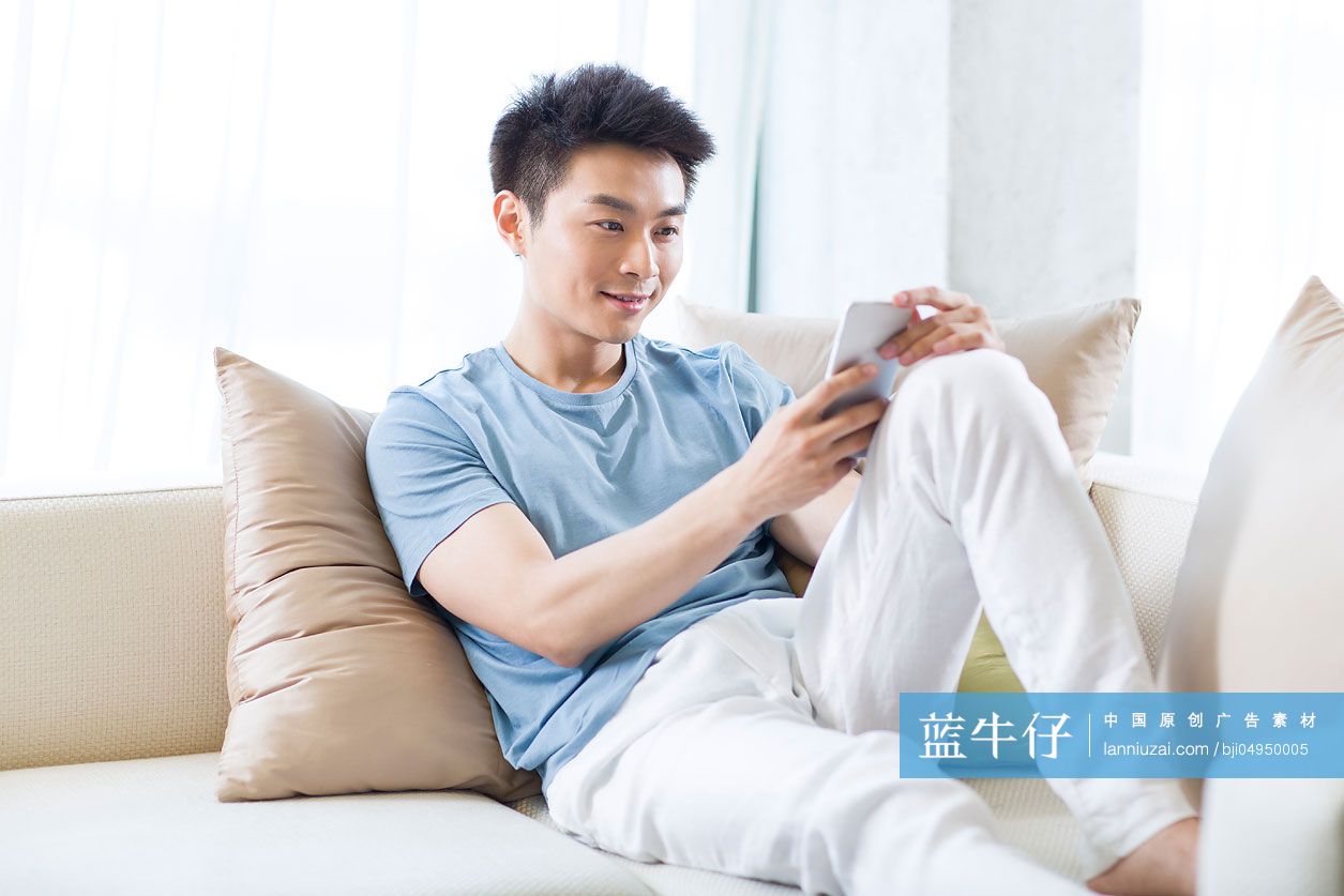年轻男子在沙发上使用手机