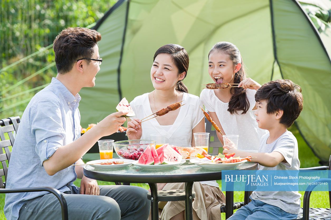 Young Chinese family picnicking outdoors