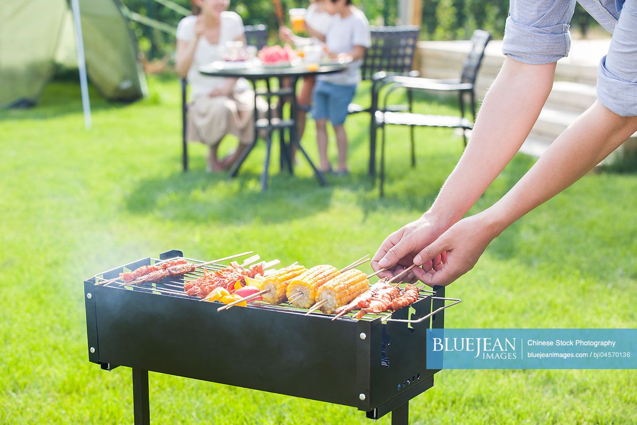 Young Chinese family barbecuing outdoors