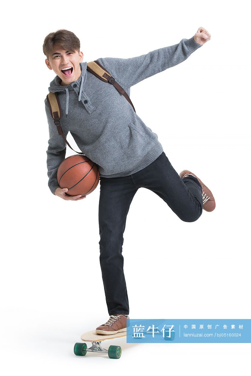 开心的男大学生拿着篮球玩滑板