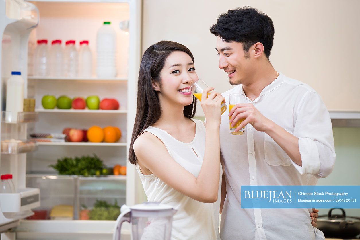 Young couple drinking juice in kitchen