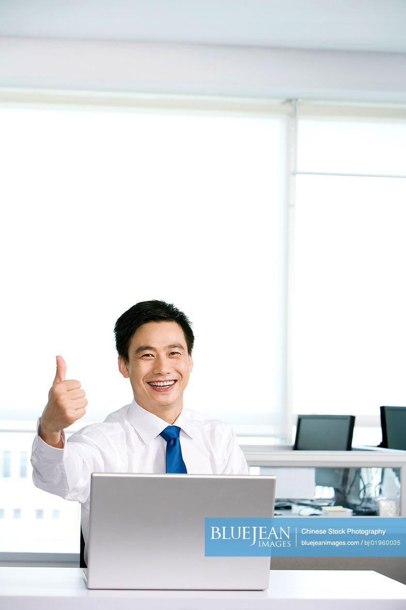 Happy Chinese office worker at his desk