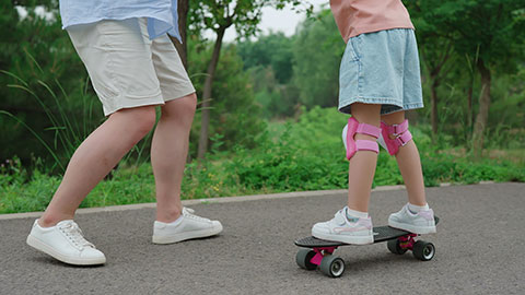 Dad taking kids skateboarding in the park