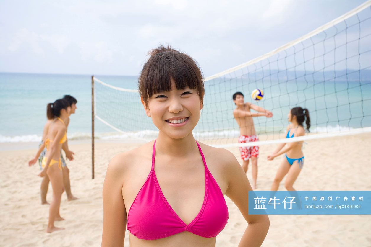 年轻女孩特写和玩沙滩排球的年轻人