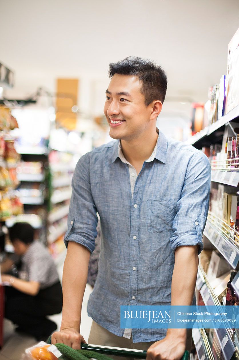 Young Chinese man shopping in supermarket
