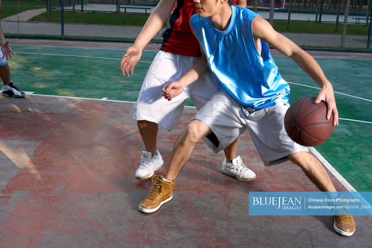 Young Chinese men playing basketball