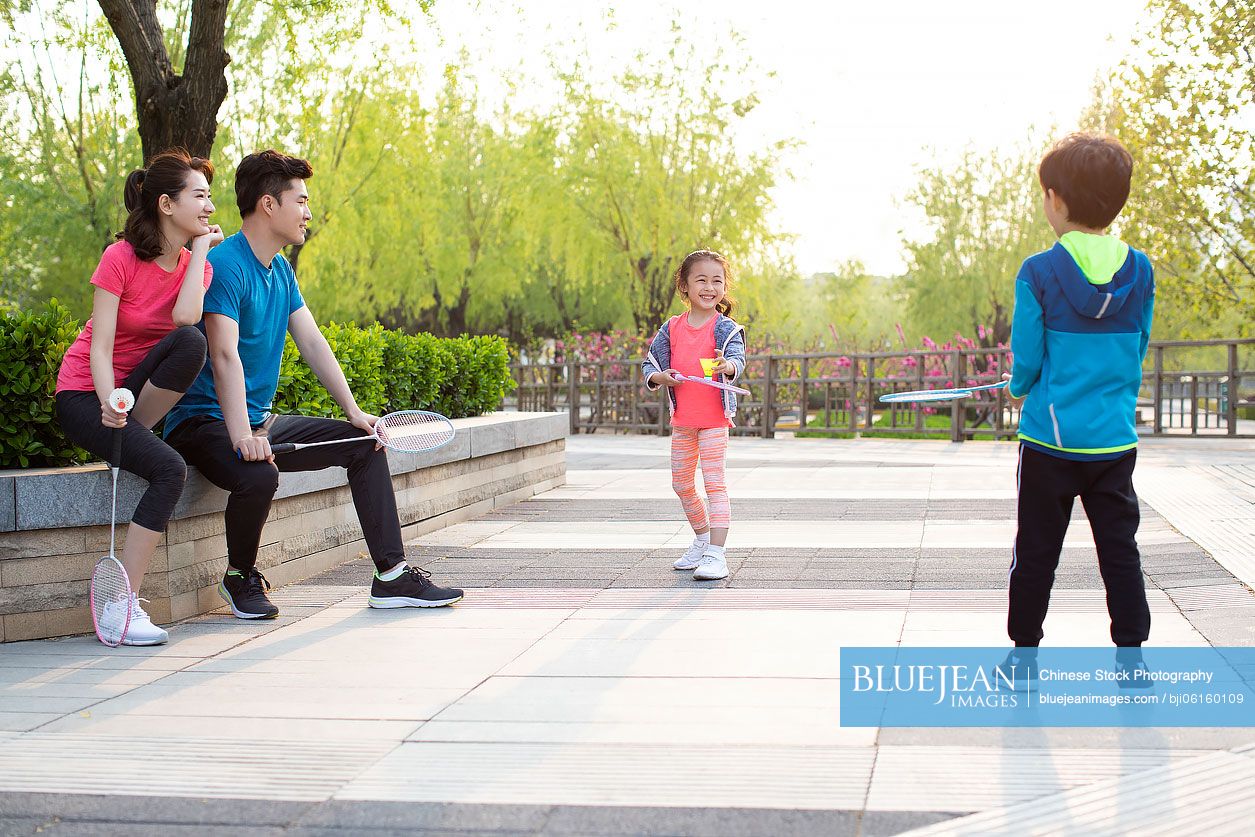 Happy young Chinese family playing badminton in park