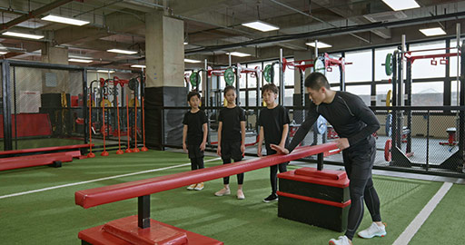 Active Chinese children having exercise class with their coach in gym,4K