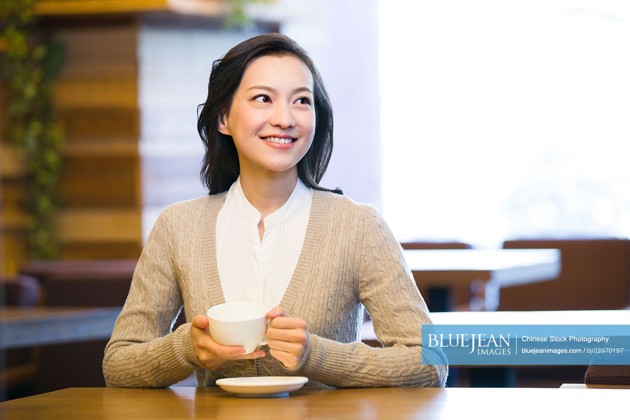Young Chinese woman enjoying coffee in coffee shop