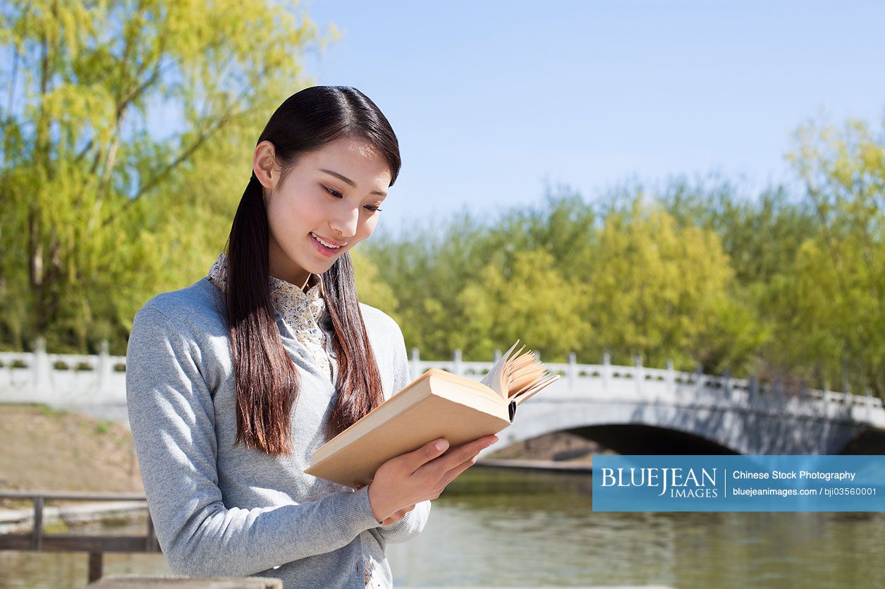 Chinese young woman reading outdoors