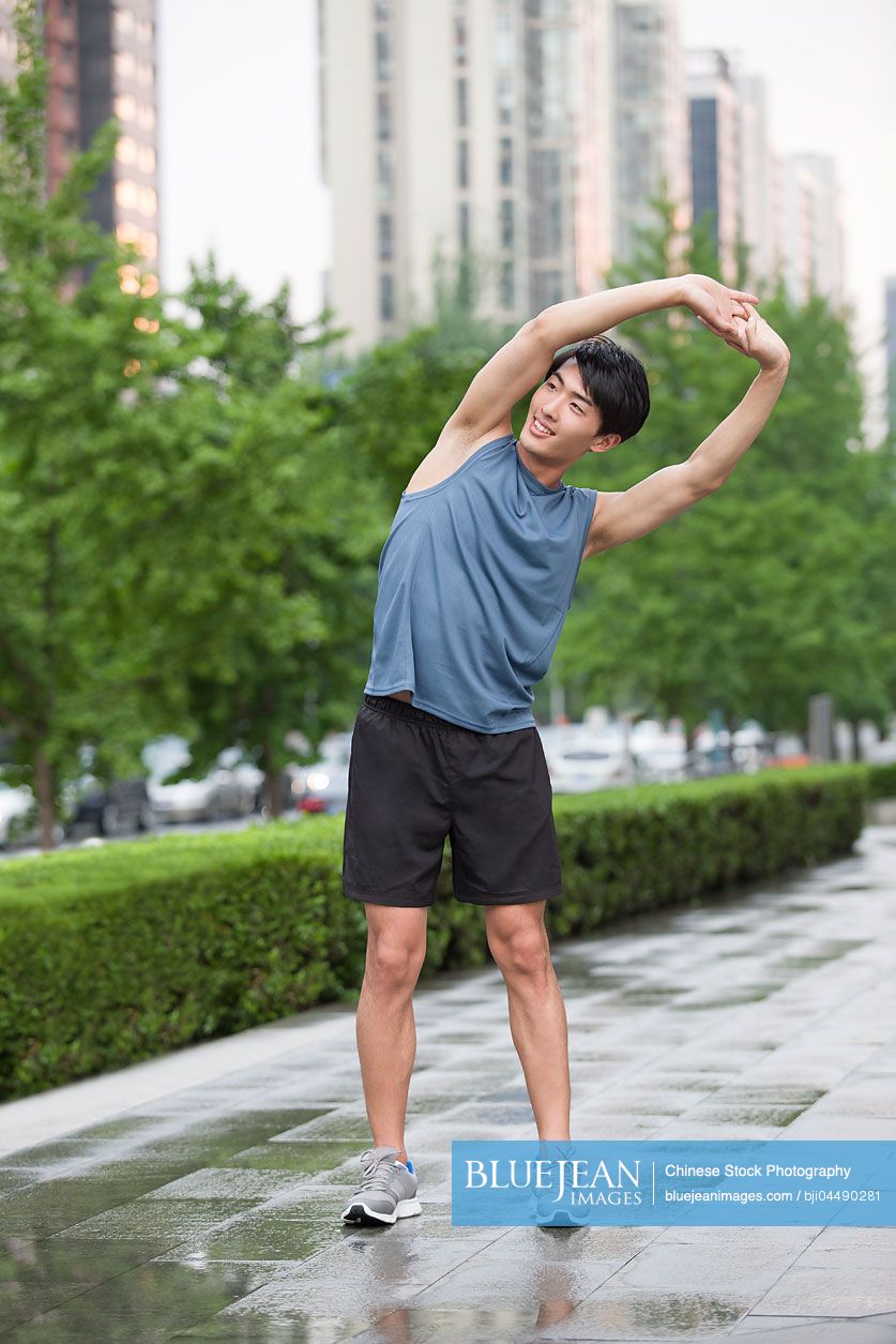 Young Chinese man stretching outside