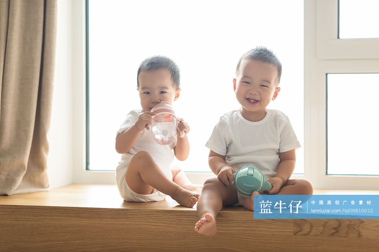可爱的龙凤胎宝宝用奶瓶喝水