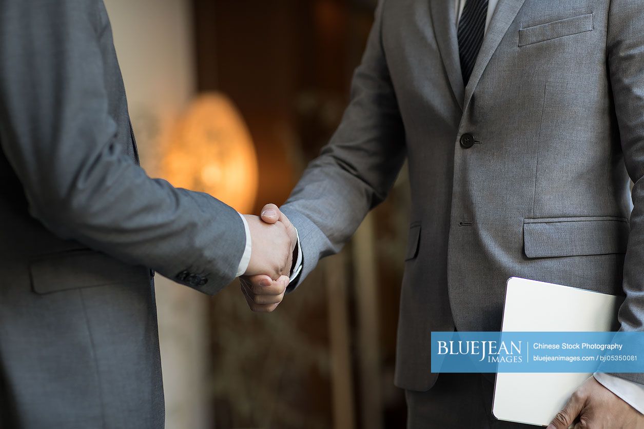 Cheerful Chinese businessmen shaking hands