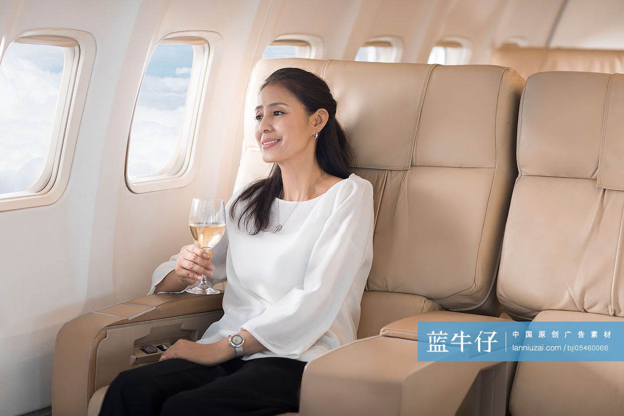 优雅的中年女士在机舱里喝葡萄酒