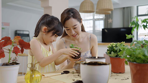 Mum and daughter enjoy potting plants together at home