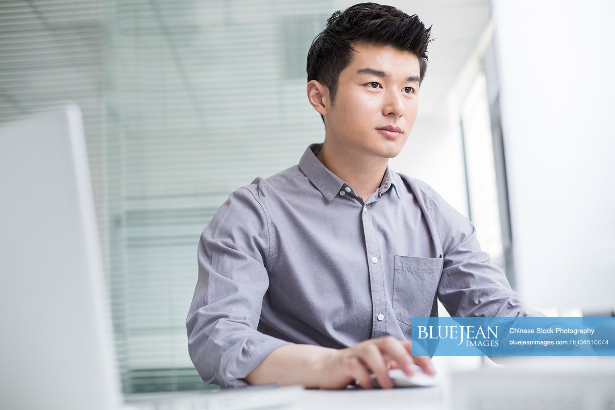 Young Chinese businessman using computer in office