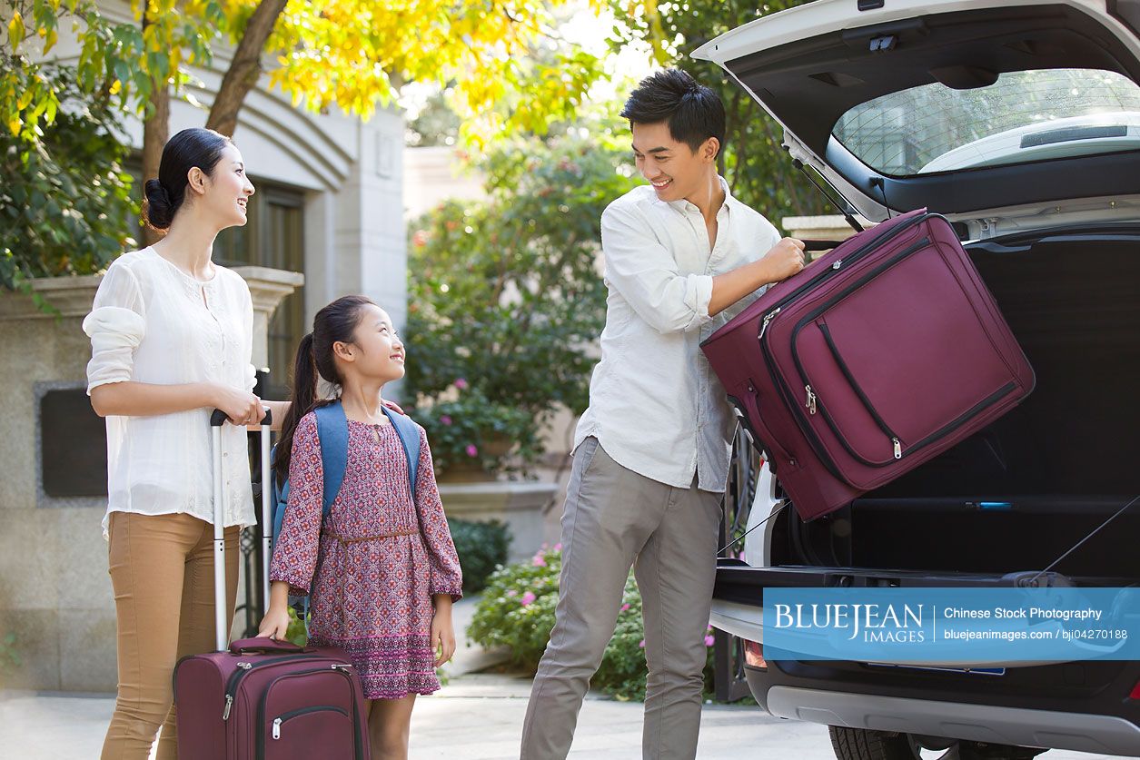 Young Chinese family packing for car trip