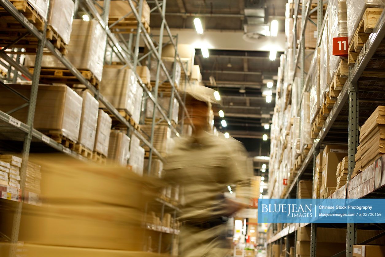 Blurred motion shot of Chinese warehouse worker pushing boxes