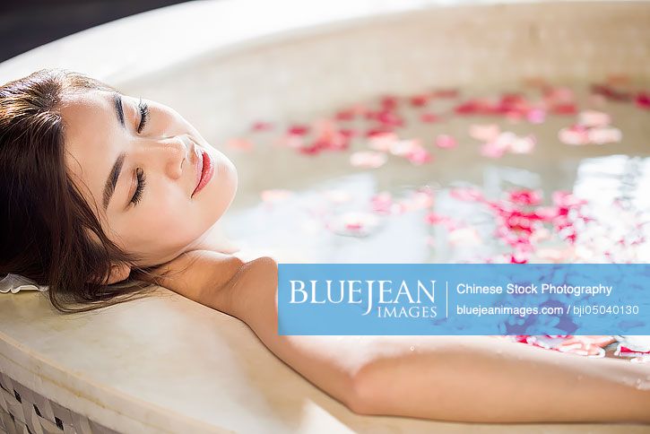 Beautiful young Chinese woman in bathtub with rose petals