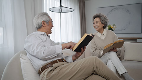 Cheerful senior Chinese couple reading book at home,4K