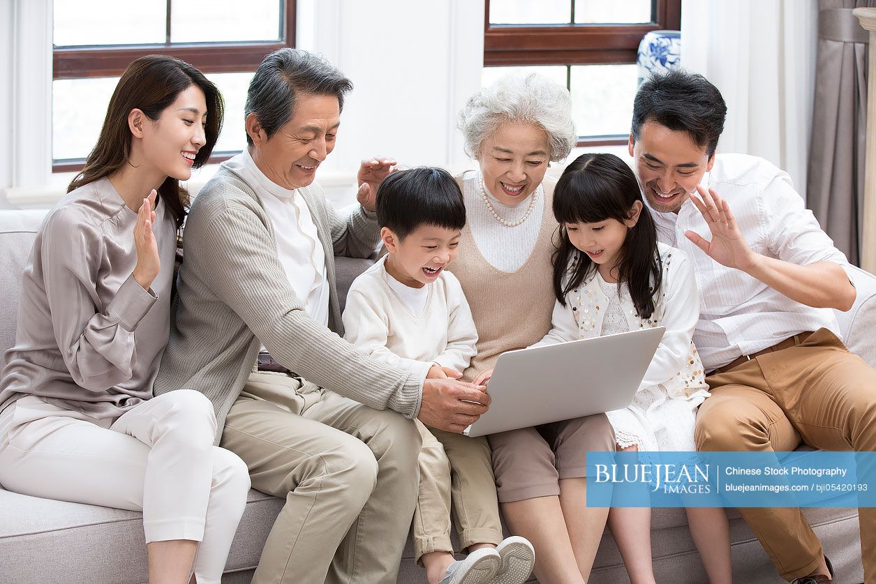 Happy Chinese family using laptop for video chatting