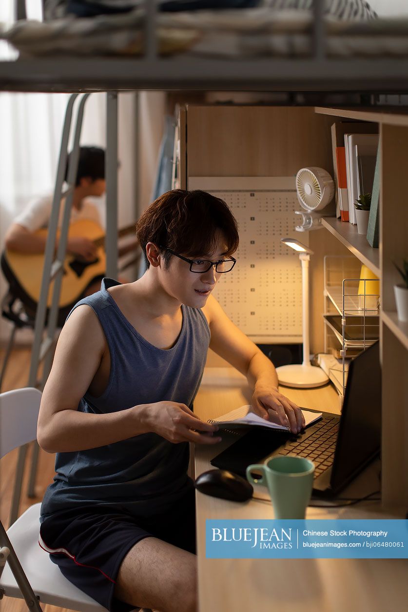 Young Chinese university student learning in dormitory