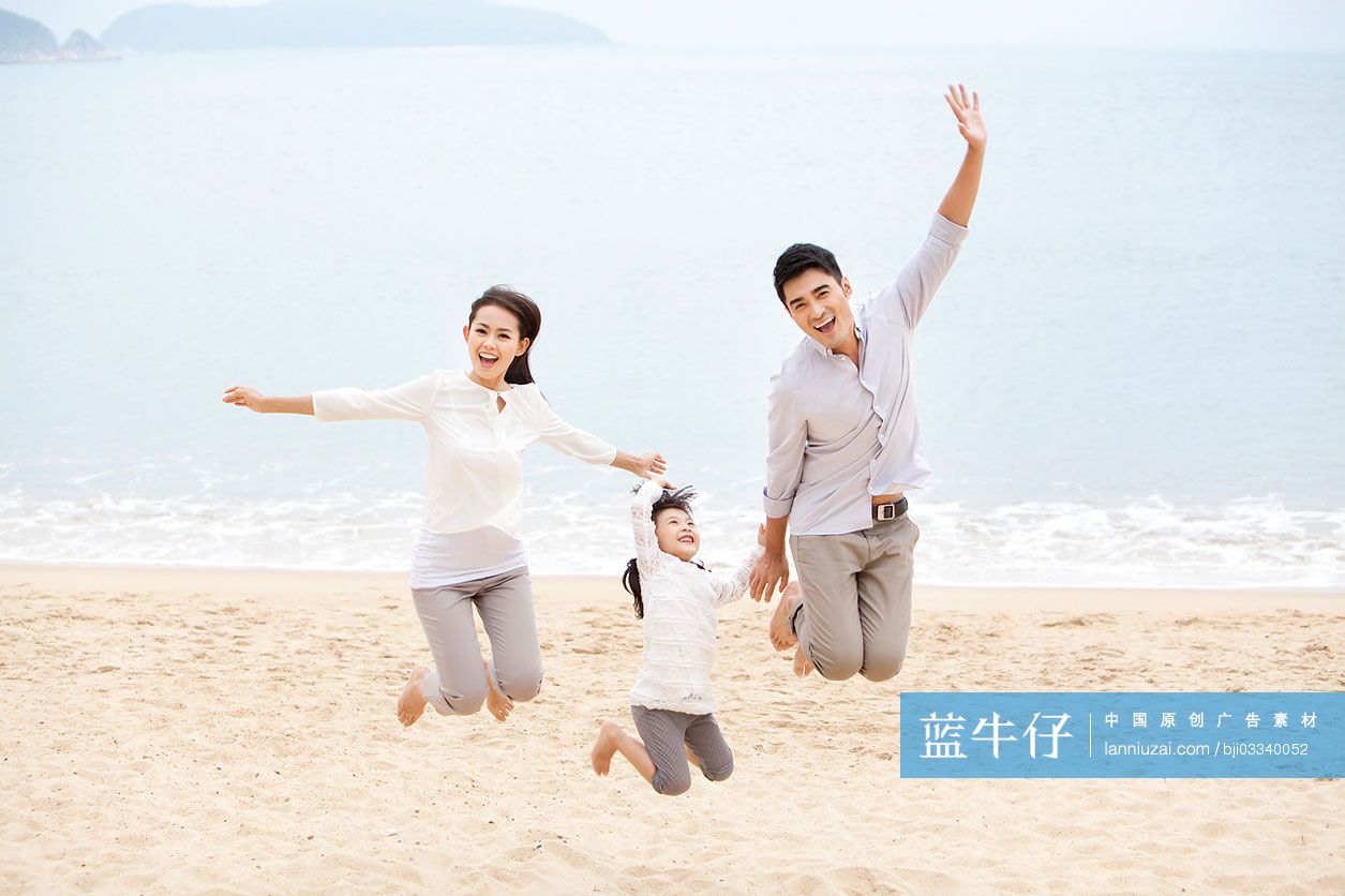 兴奋的一家三口在沙滩上跳跃