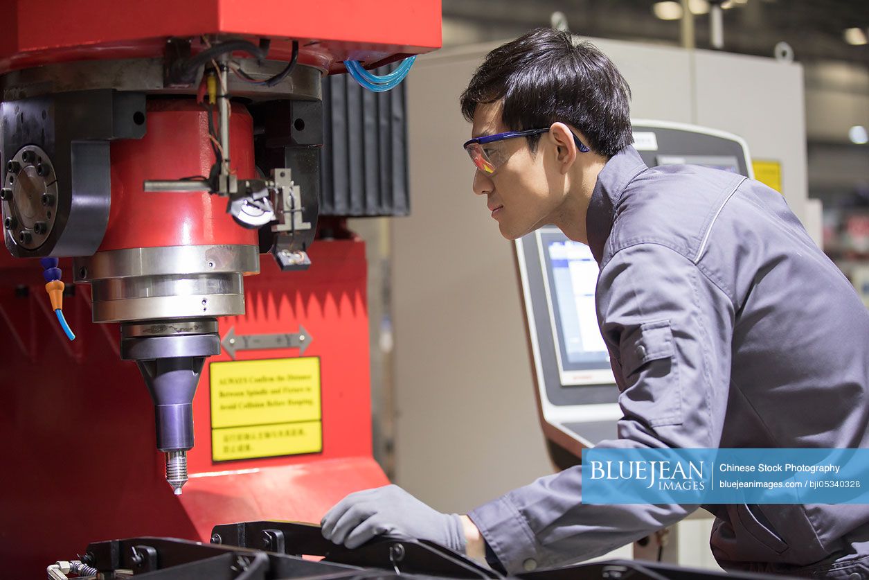 Confident Chinese engineer working in the factory