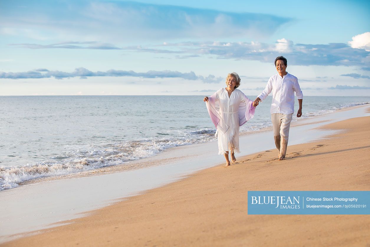 Happy senior Chinese couple walking on beach-High-res stock photo for ...