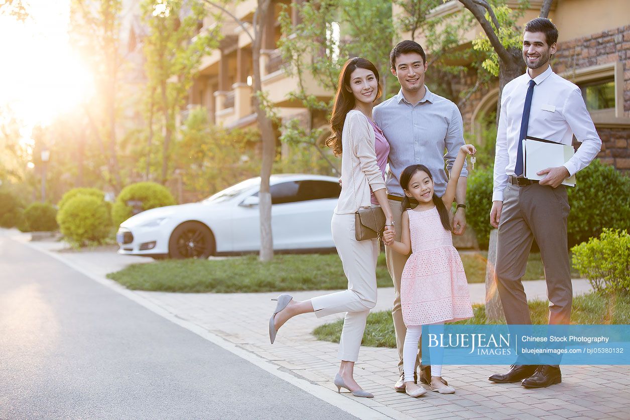 Happy young Chinese family receiving house key from real estate agent