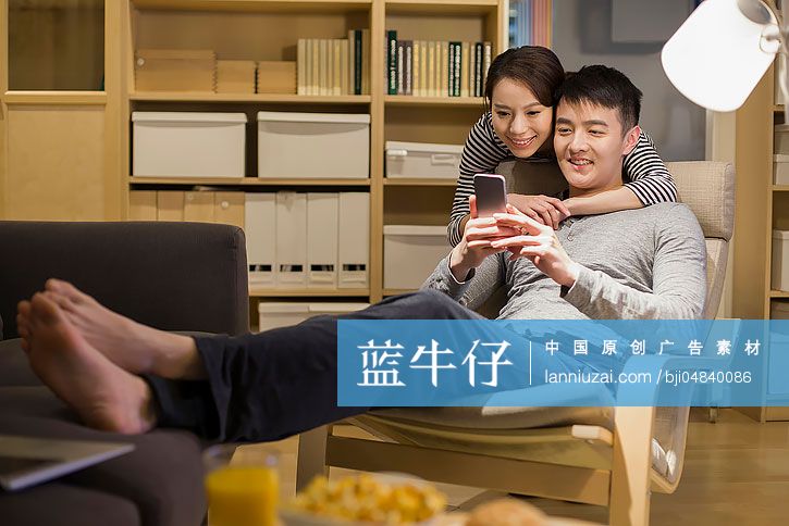 年轻情侣在客厅使用手机