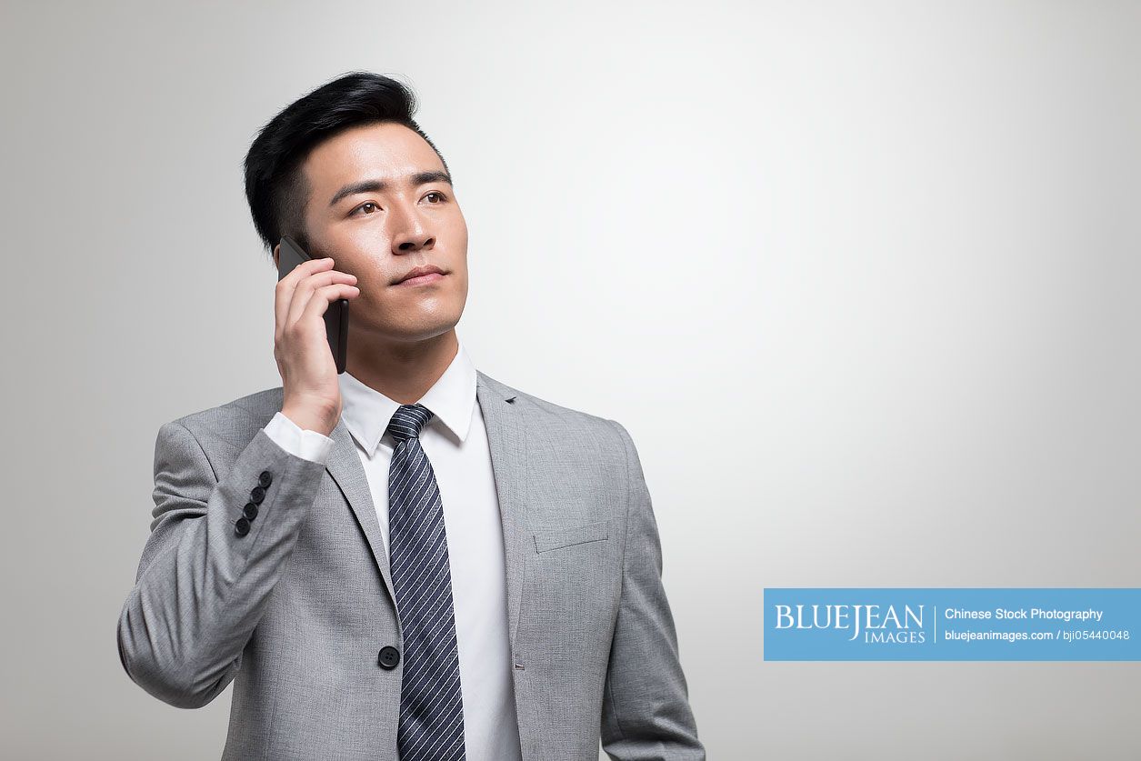 Young Chinese businessman talking on cell phone