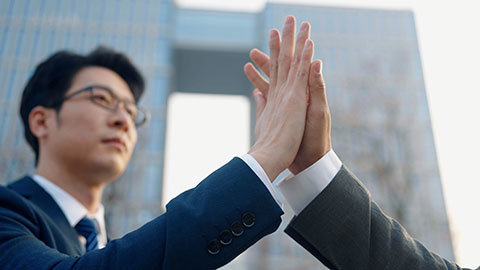 Confident Chinese business people holding hands outdoors