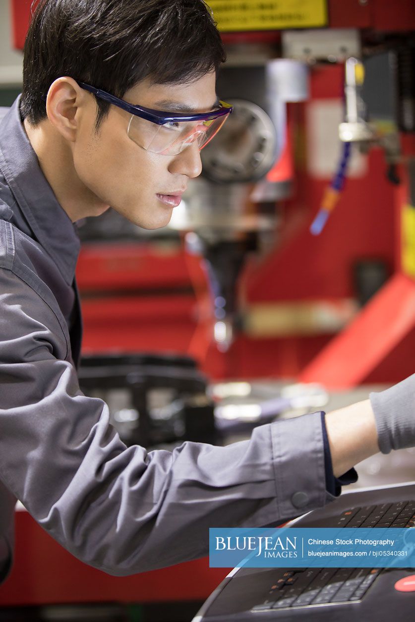 Confident Chinese engineer working in the factory