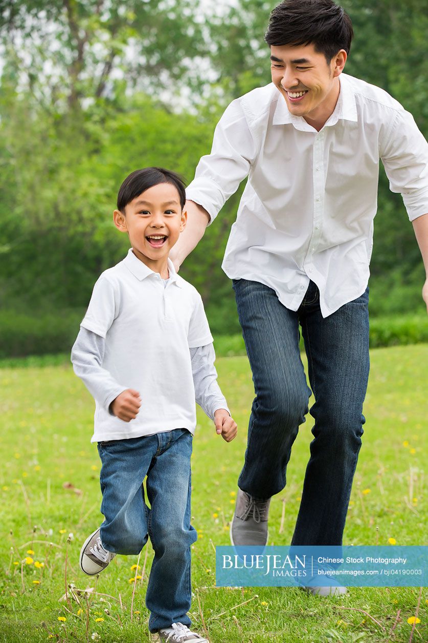 Happy Chinese father and son running on the grass