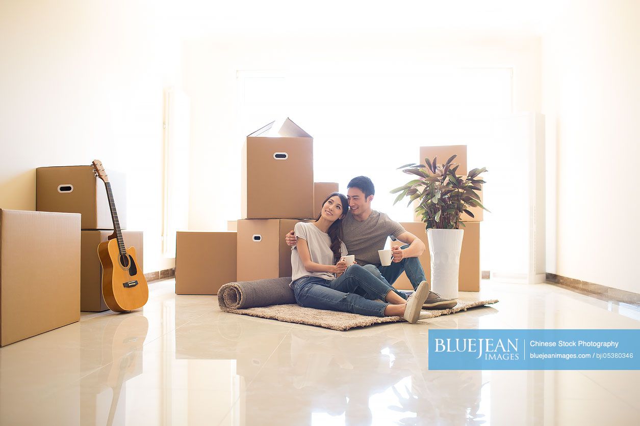 Happy young Chinese couple moving to a new house