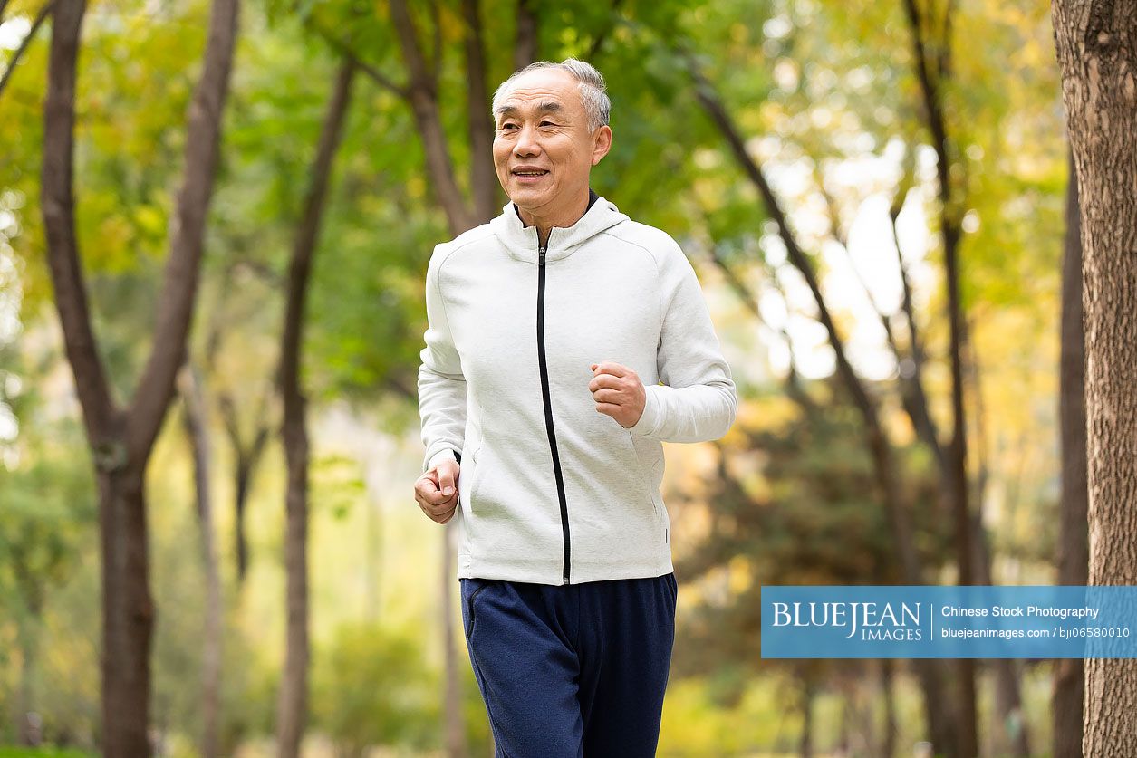Happy senior Chinese man running in the park