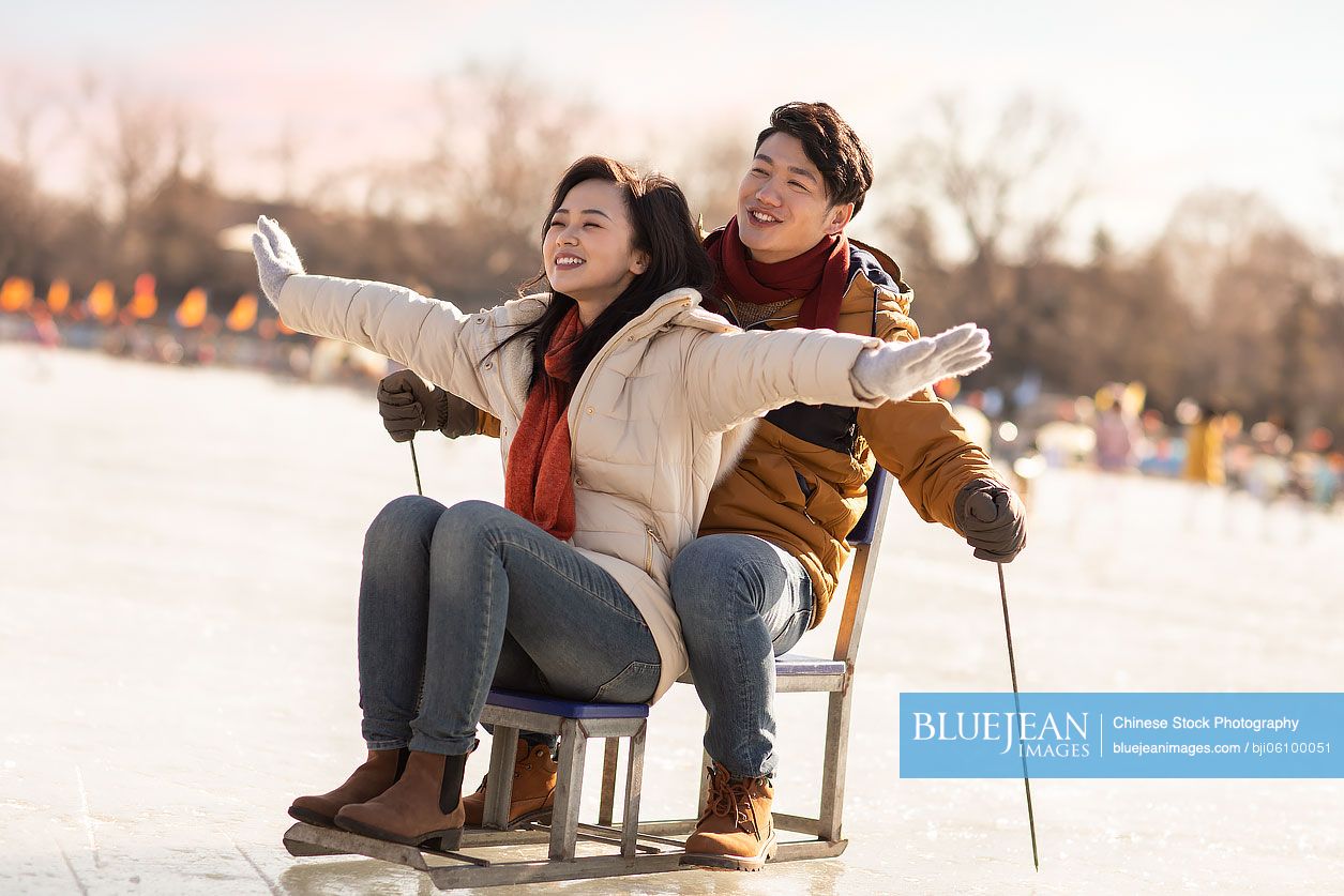 Happy young Chinese couple playing on ice
