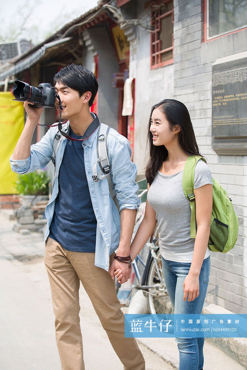 年轻情侣拿着相机在北京胡同里旅游