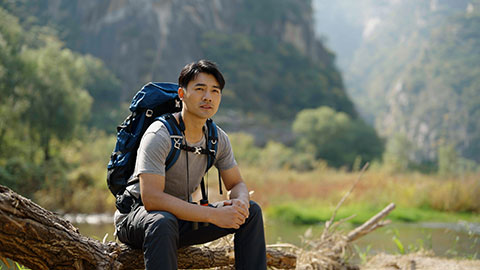 Young Chinese man hiking outdoors