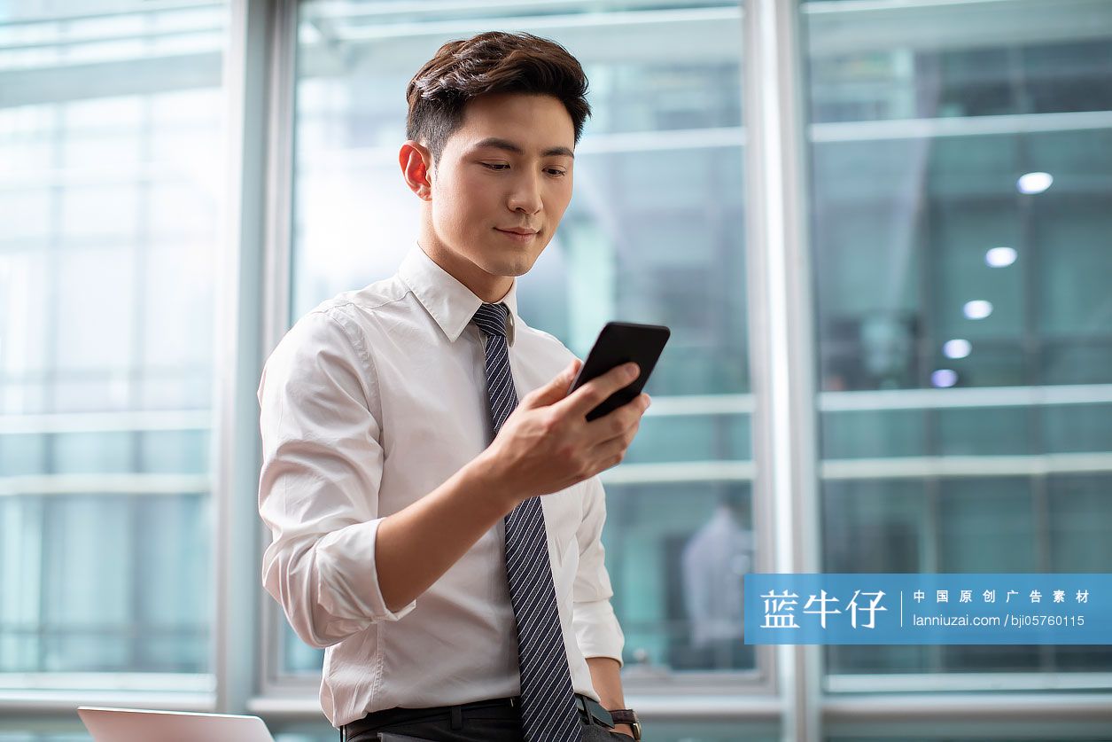 自信的商务男士在办公室使用手机