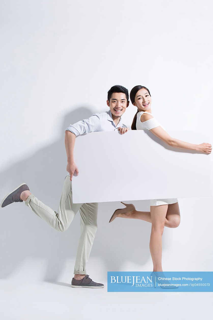 Happy young Chinese couple holding a whiteboard