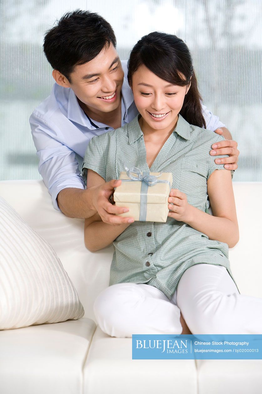 Young Chinese man giving young woman a gift