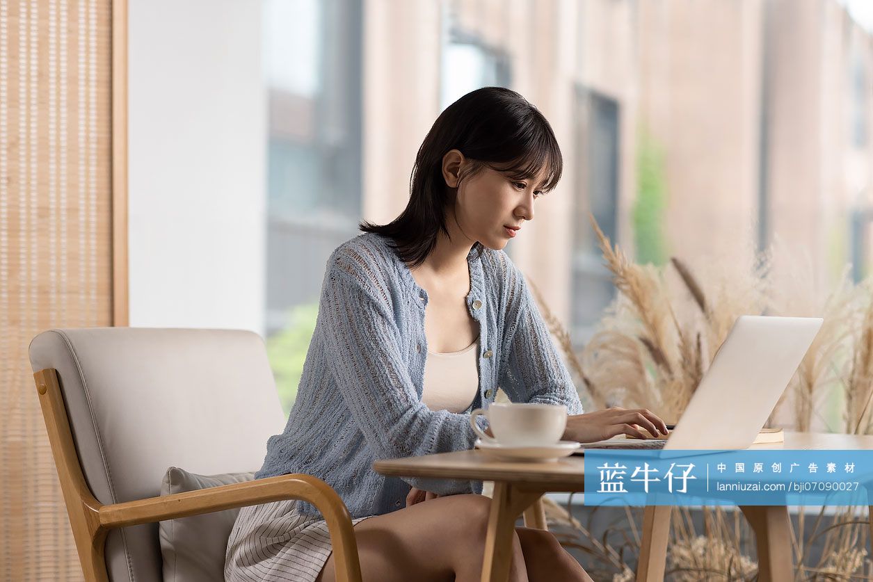 年轻女子在咖啡馆使用笔记本电脑