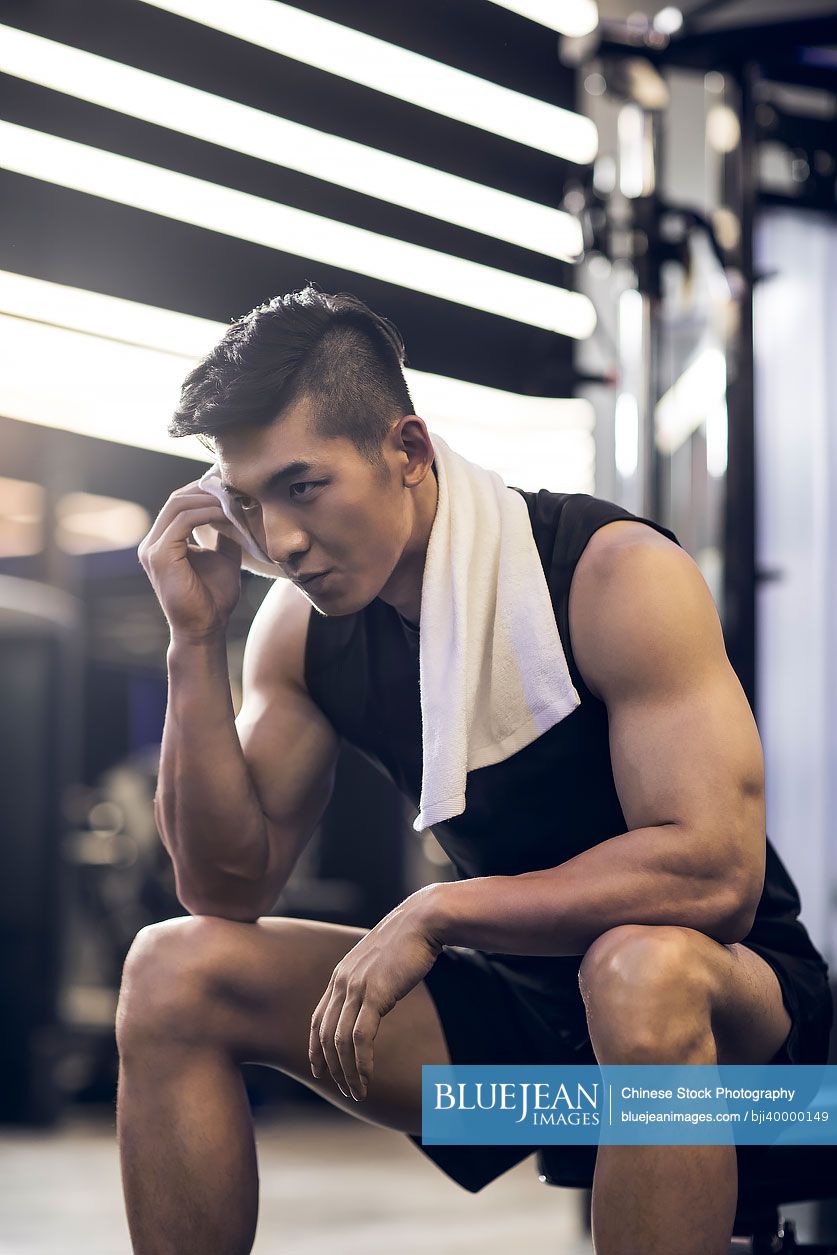 Young Chinese man taking a break from workout at gym