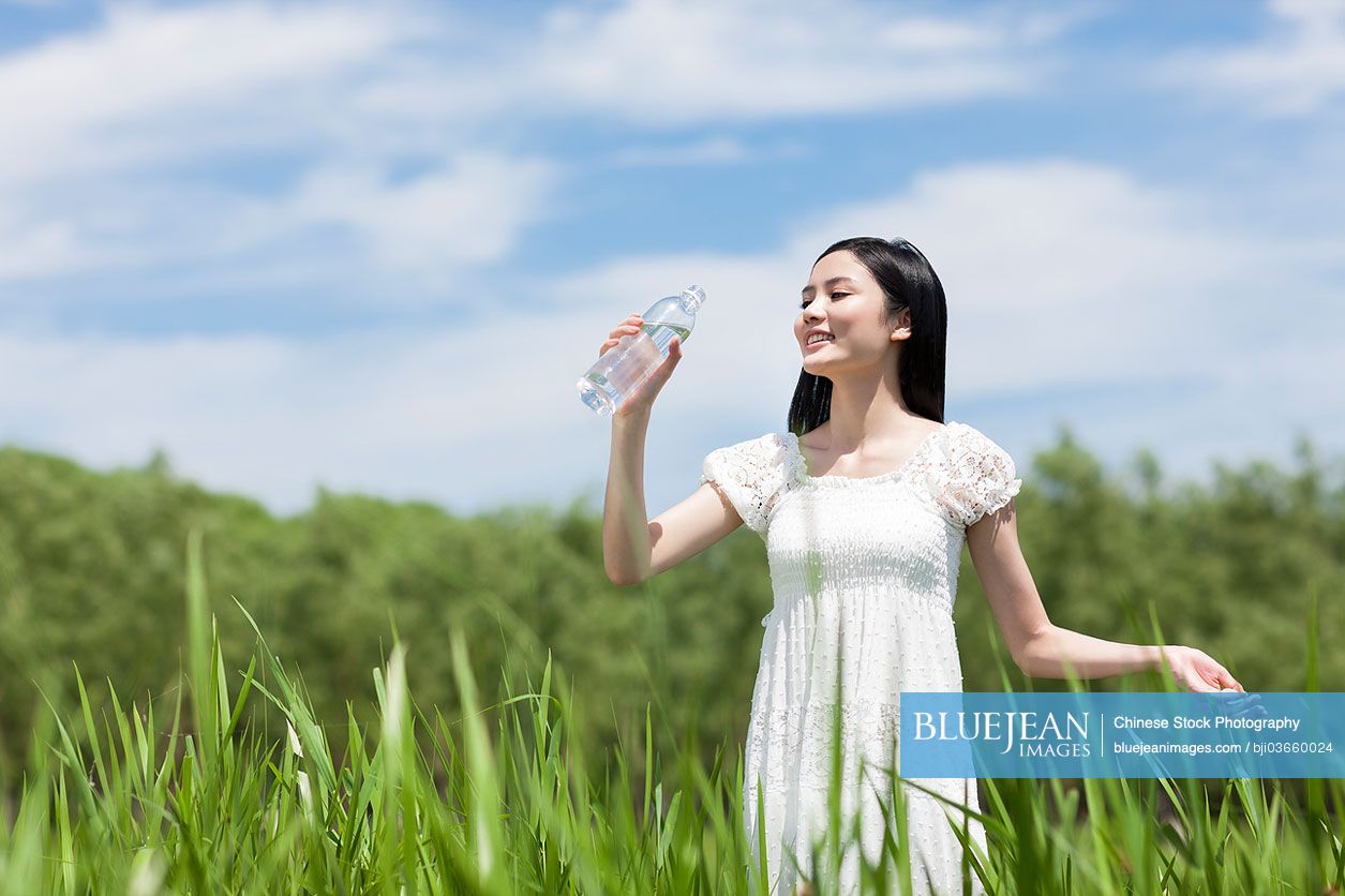 Young Chinese woman drinking water outdoors