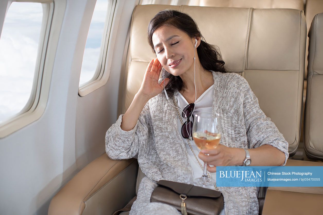 Mature Chinese woman relaxing on airplane