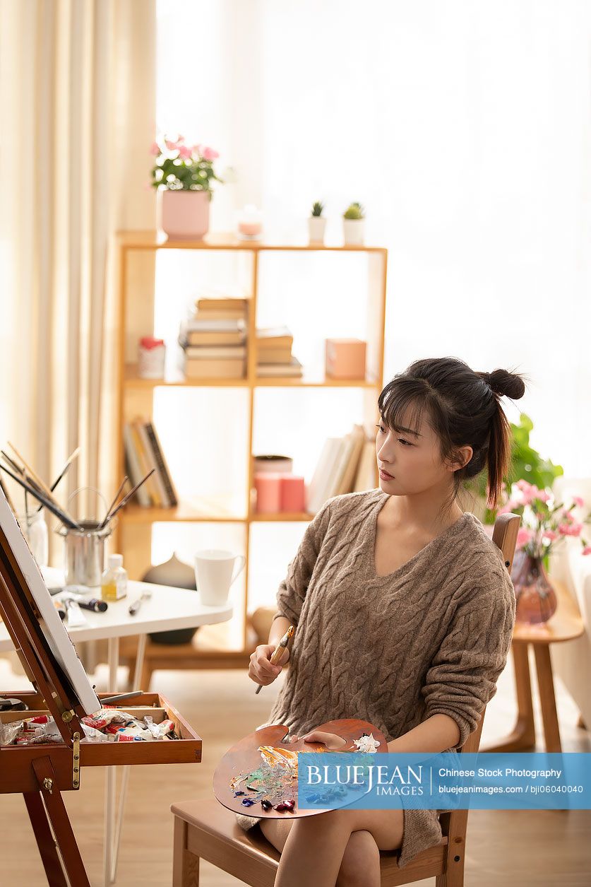 Young Chinese woman painting at home