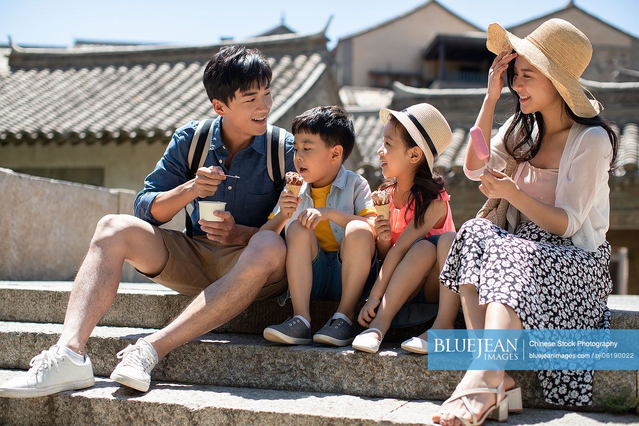 Happy young Chinese family eating ice cream outside