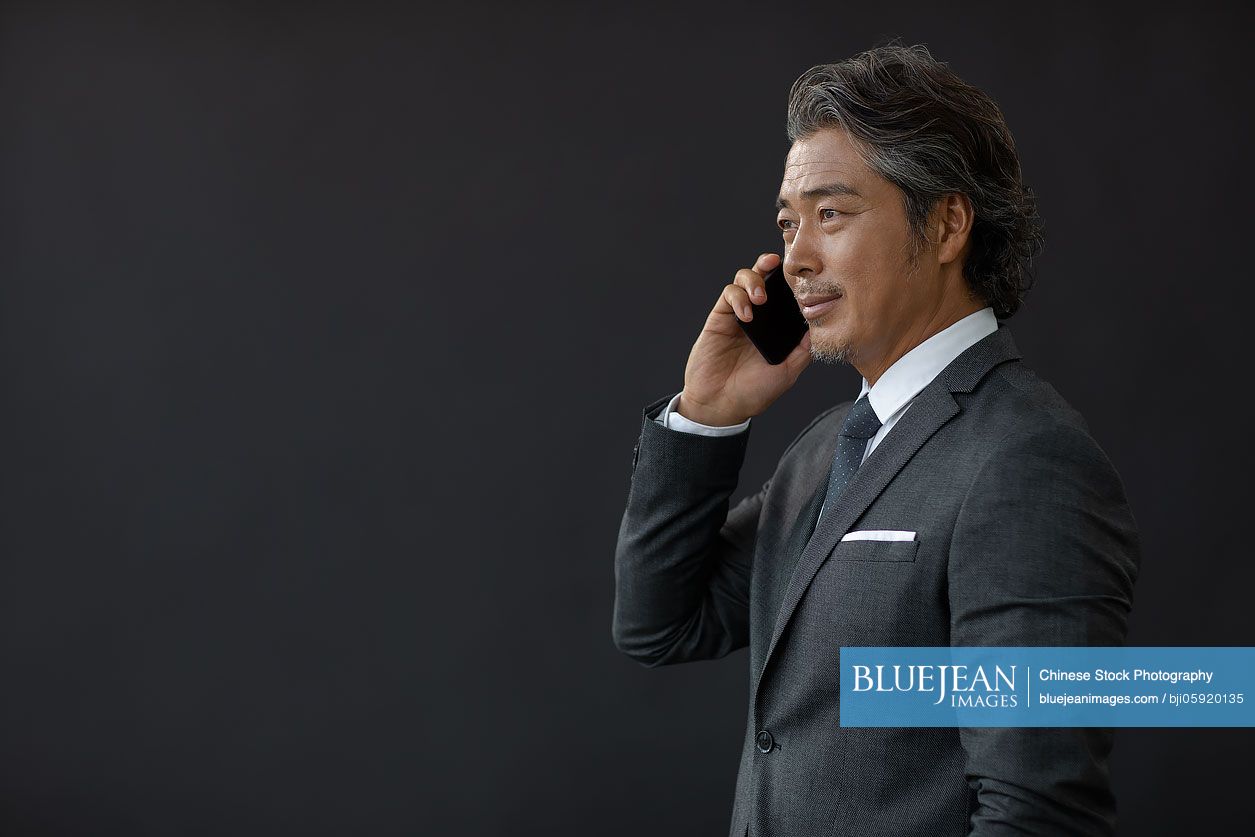 Successful Chinese businessman using smartphone